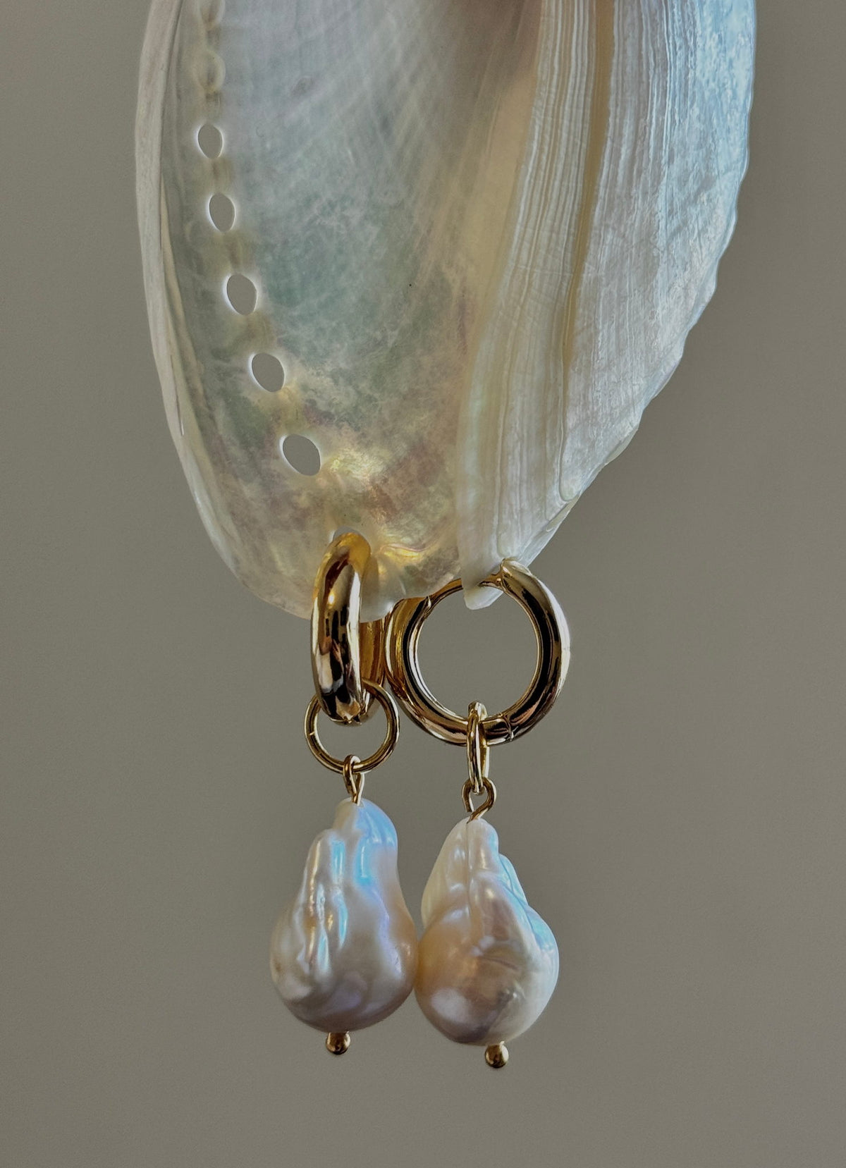 Baroque Pearl Hoops hanging from an abalone shell, close-up of the pearl drops